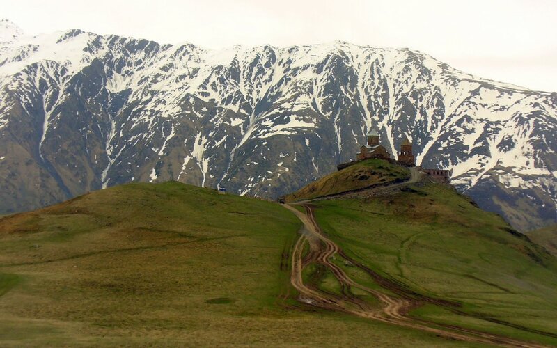 Monastery on a hill with snowy mountains