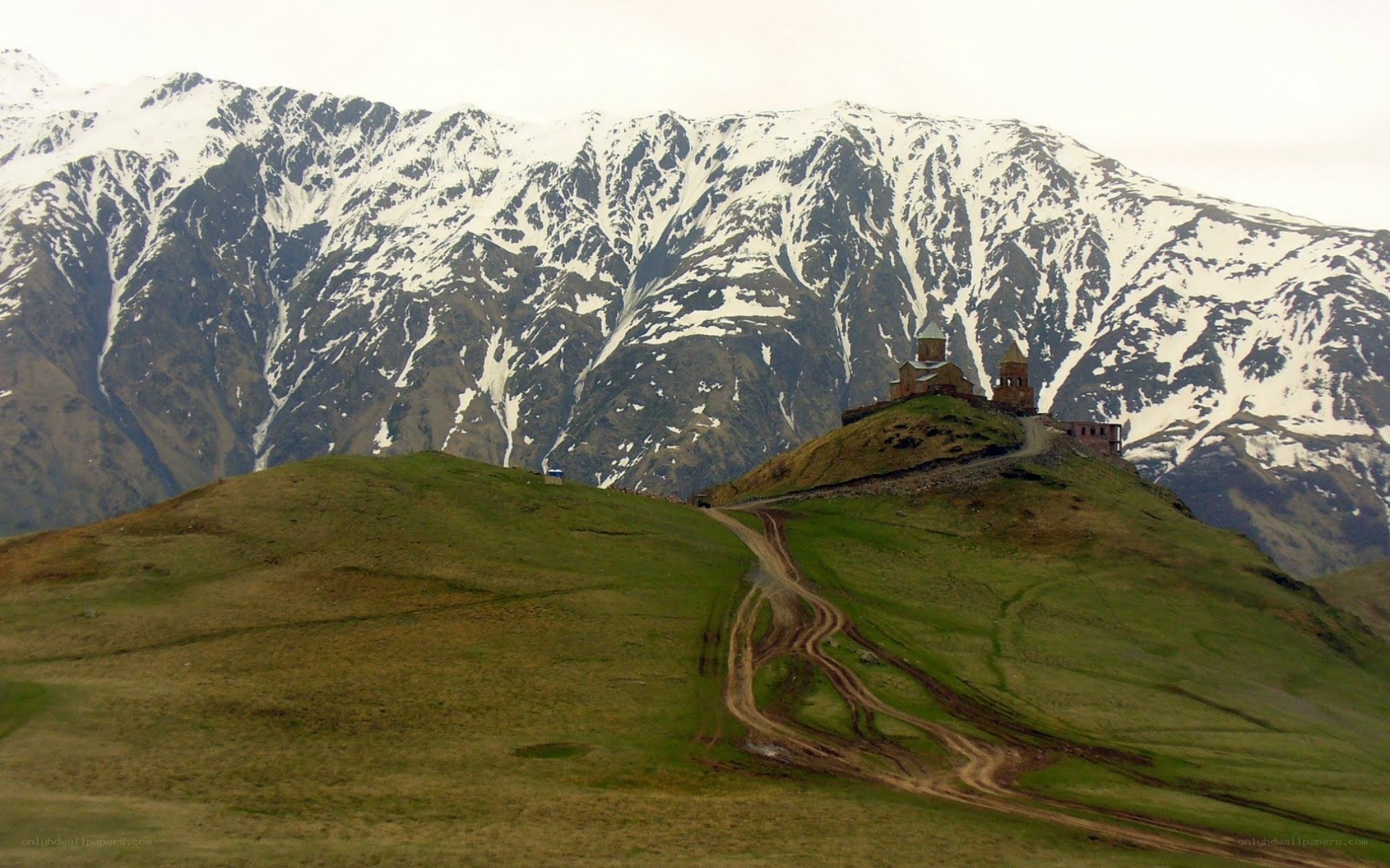 Monastery on a hill with snowy mountains