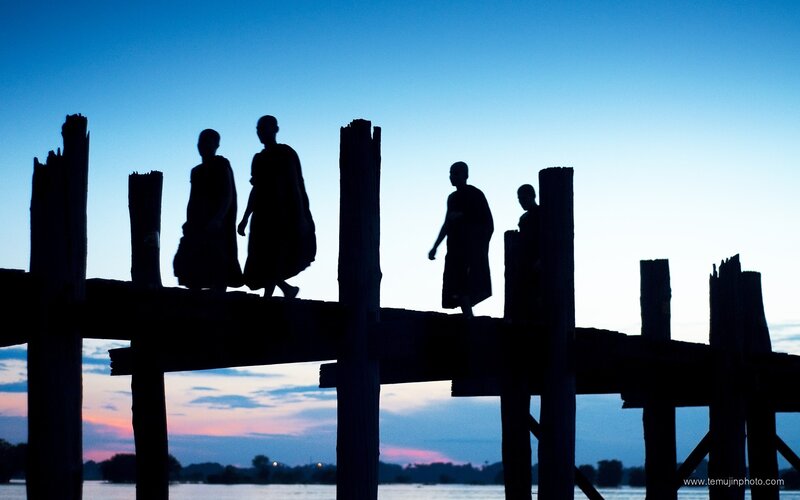Monks on a wooden bridge at dusk