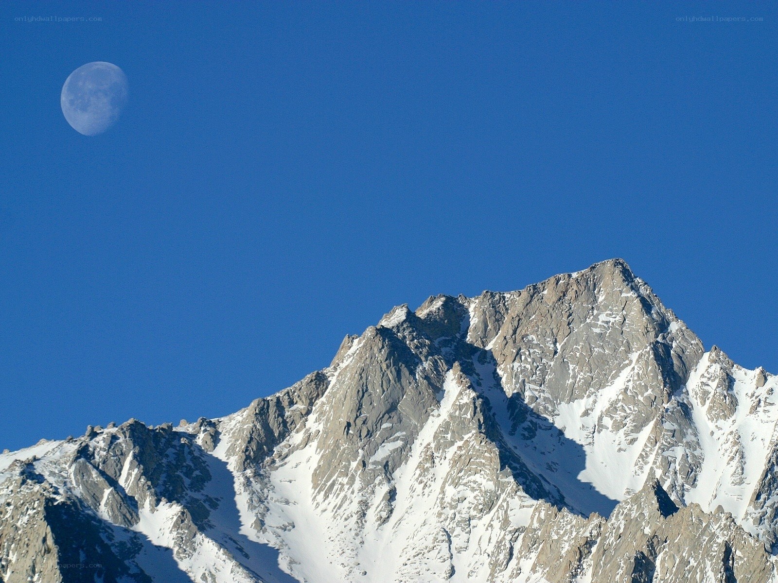 Moon above snowy mountain peak
