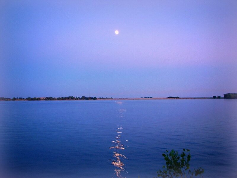 Moon over calm lake at dusk