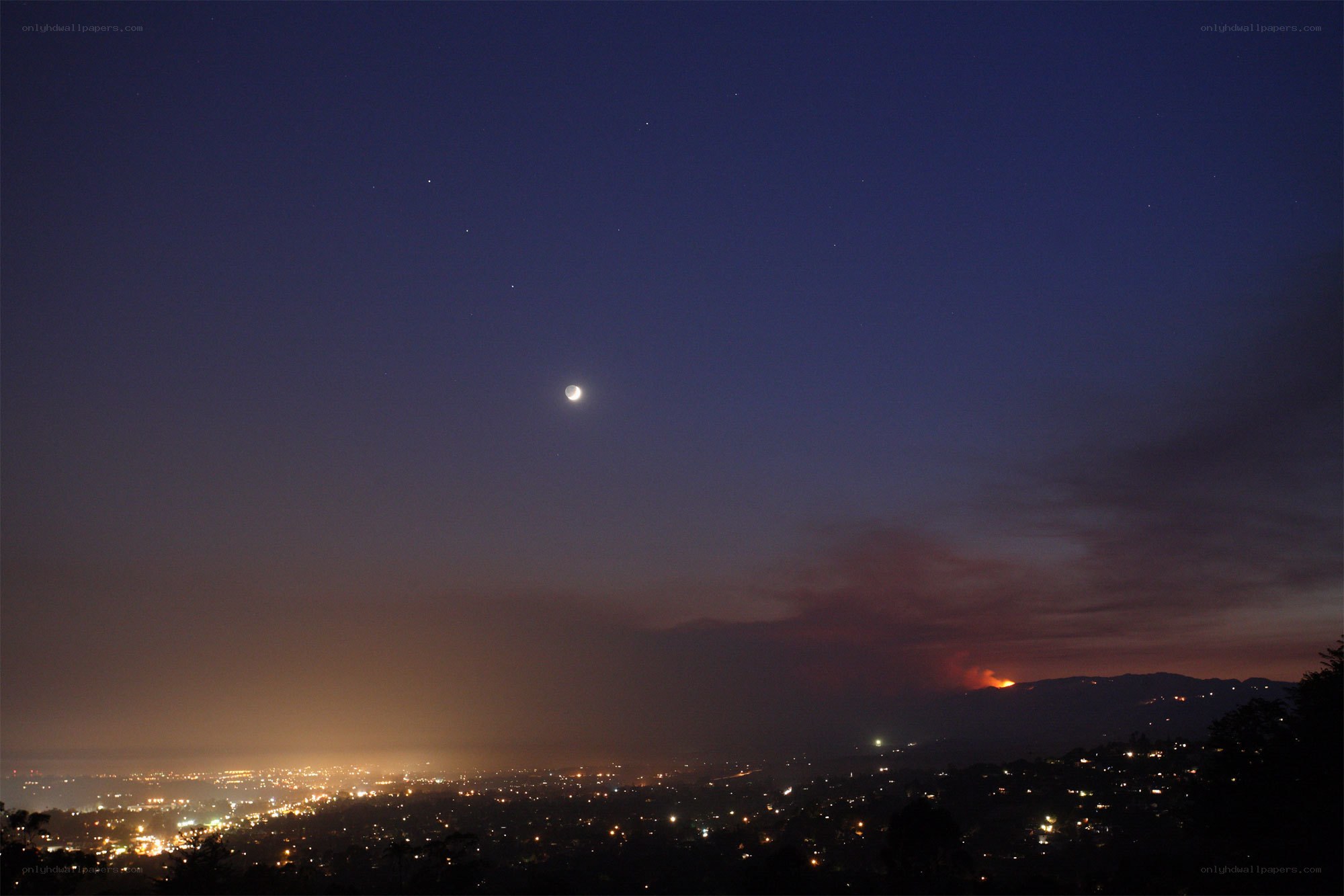 Moon over city with wildfire