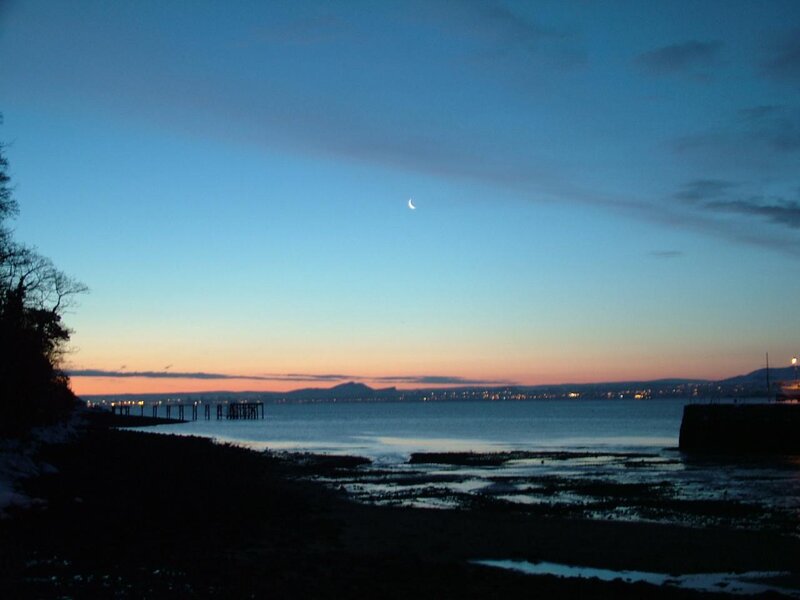 Moon over coastal bay at dusk