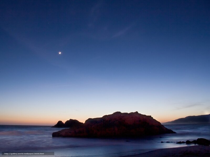 Moon over coastal rocks at dusk