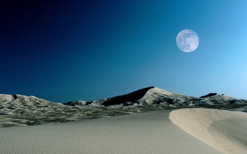 Moon over desert dunes