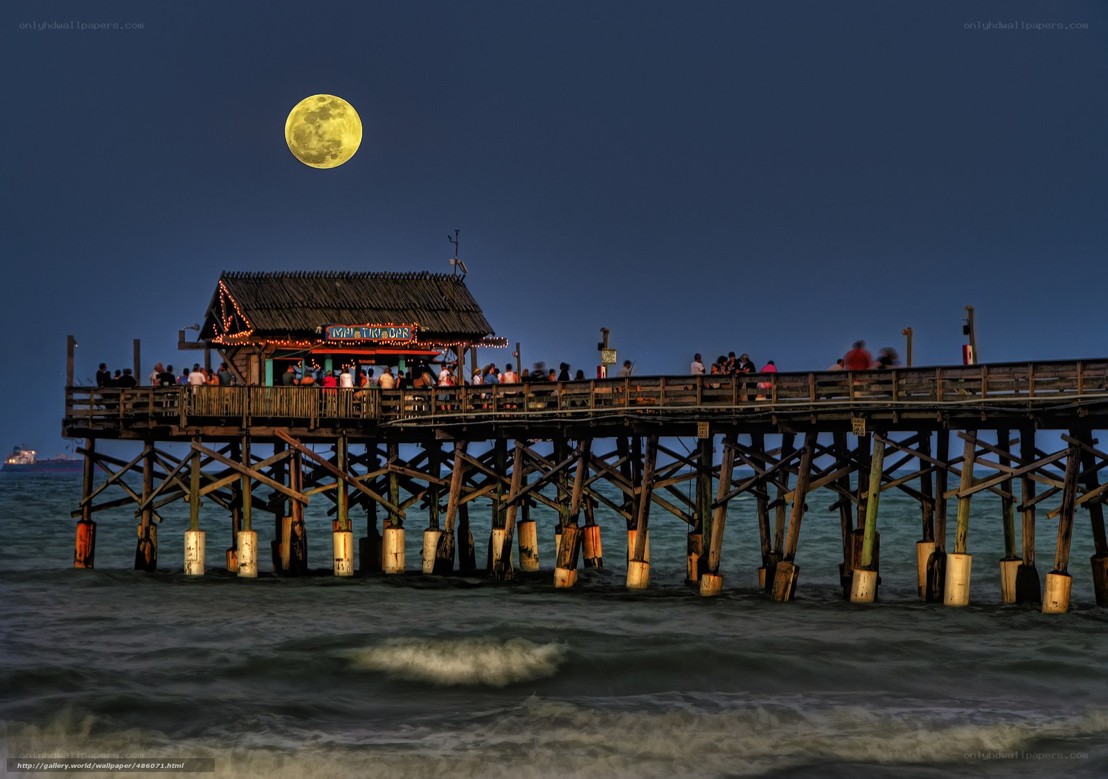 Moon over pier at night