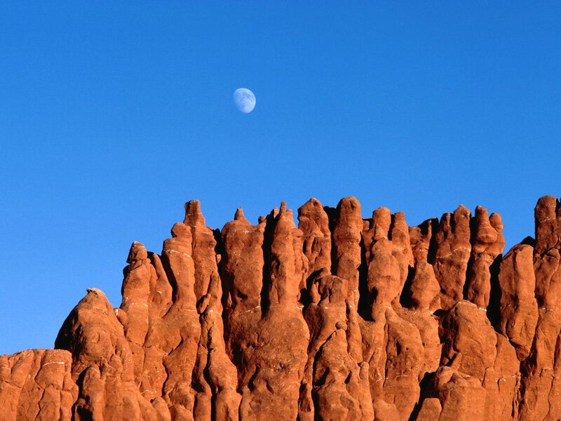 Moon over red rock formations