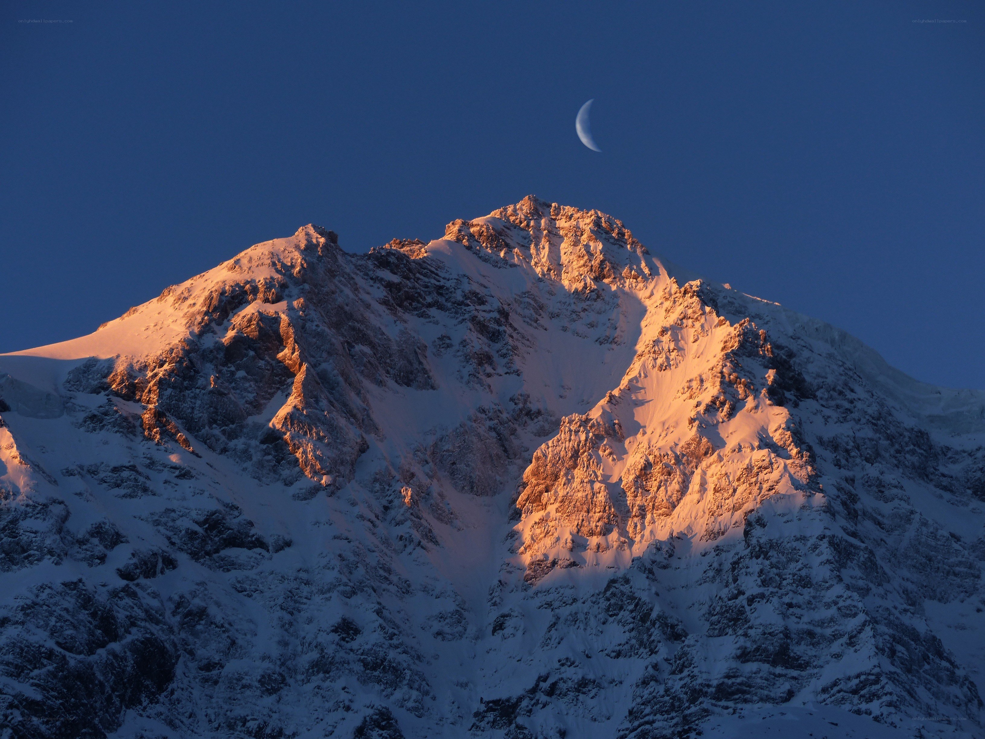 Moon over snow-capped mountain