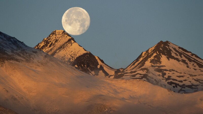 Moon over snow-capped mountains