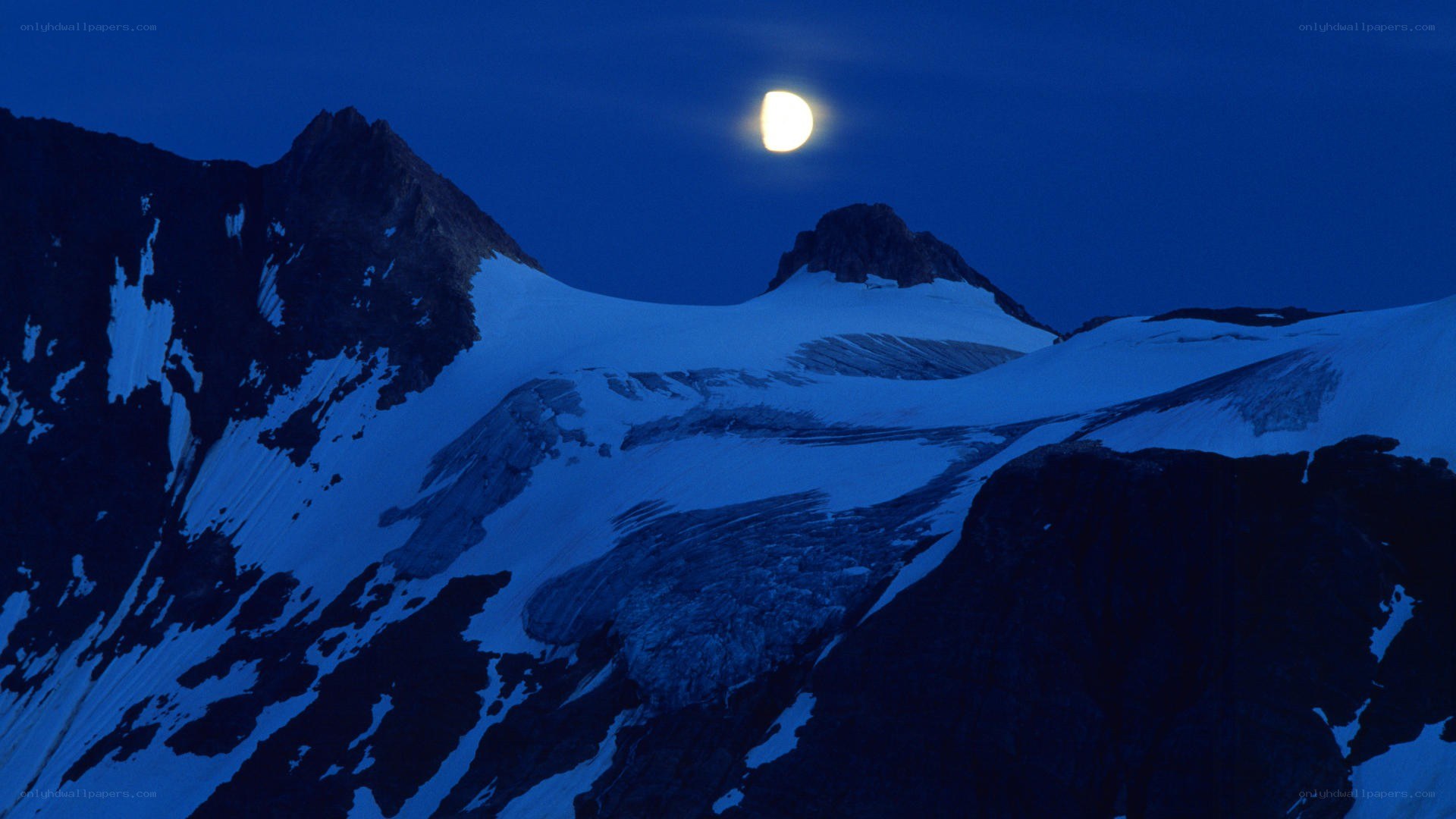 Moon over snow-capped mountains