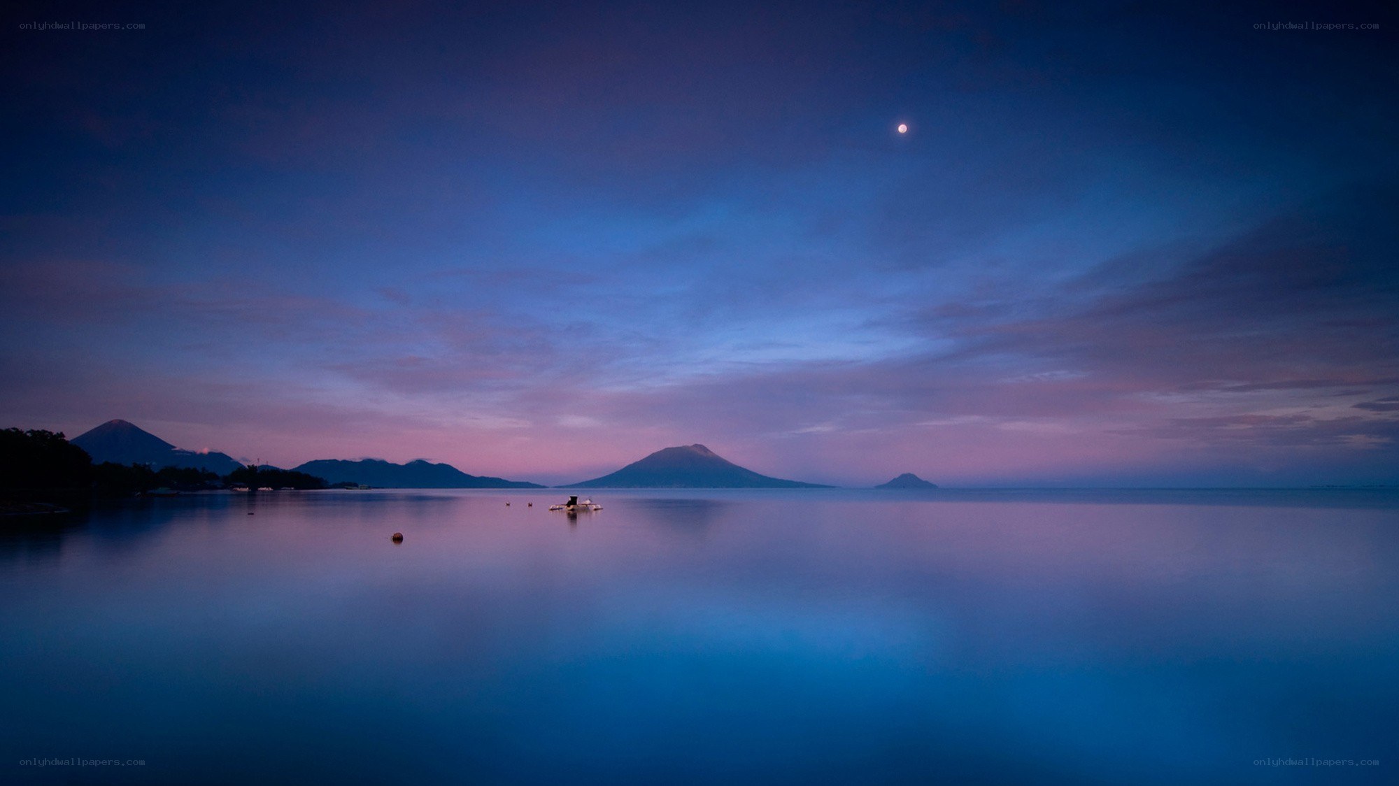Moon over volcanic lake at dusk
