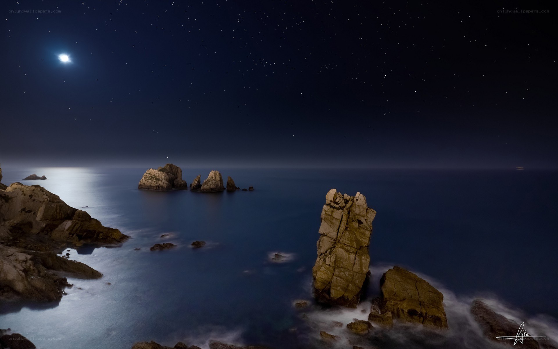 Moonlit coastal rocks at night