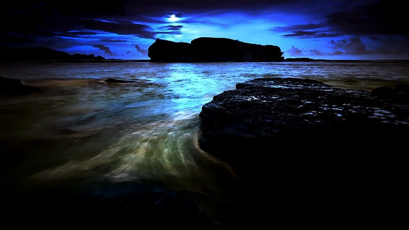 Moonlit coastal rocks at night