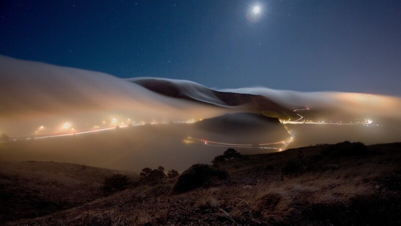 Moonlit fog over winding road