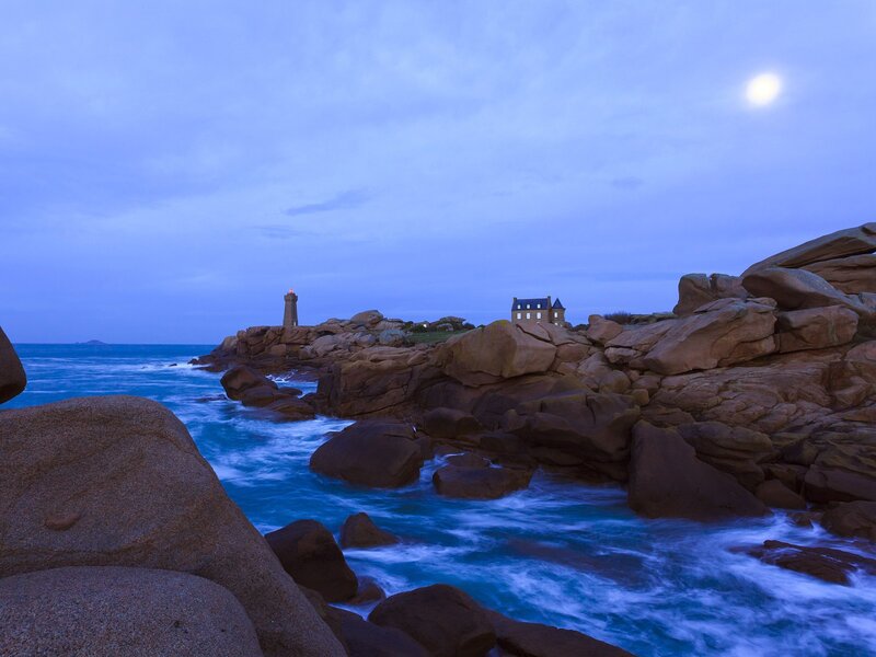 Moonlit lighthouse on rocky coast