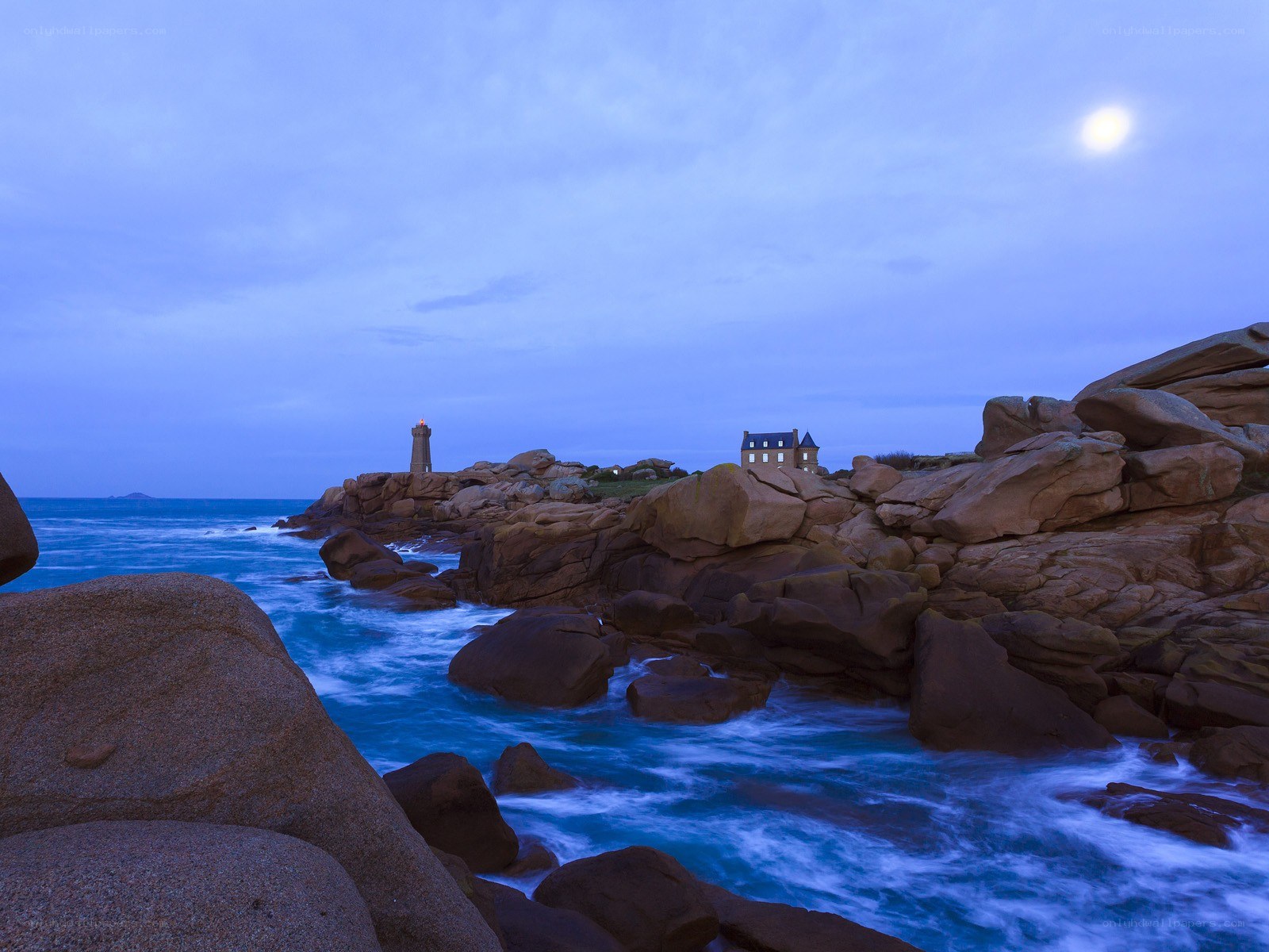 Moonlit lighthouse on rocky coast