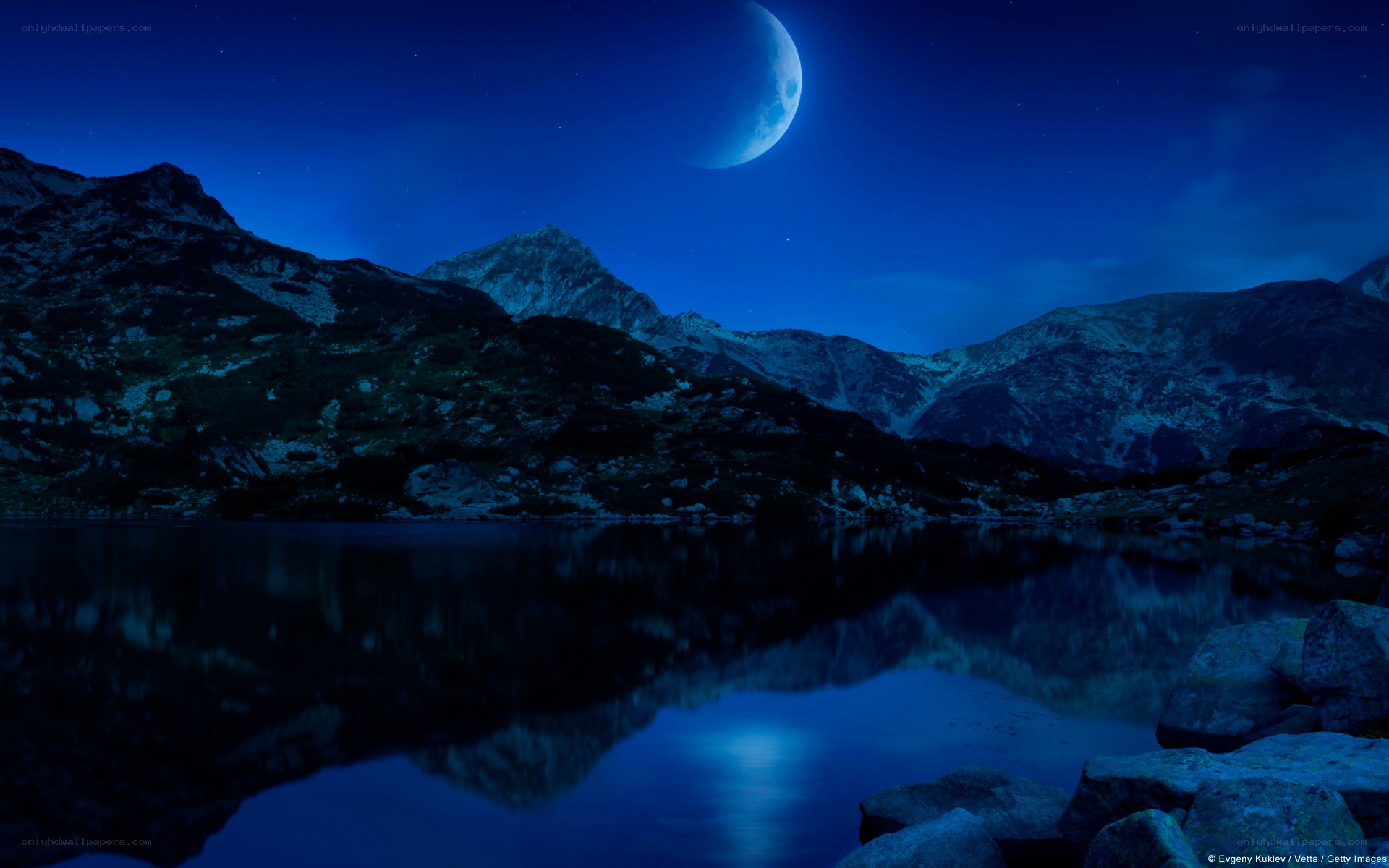 Moonlit mountain lake at night