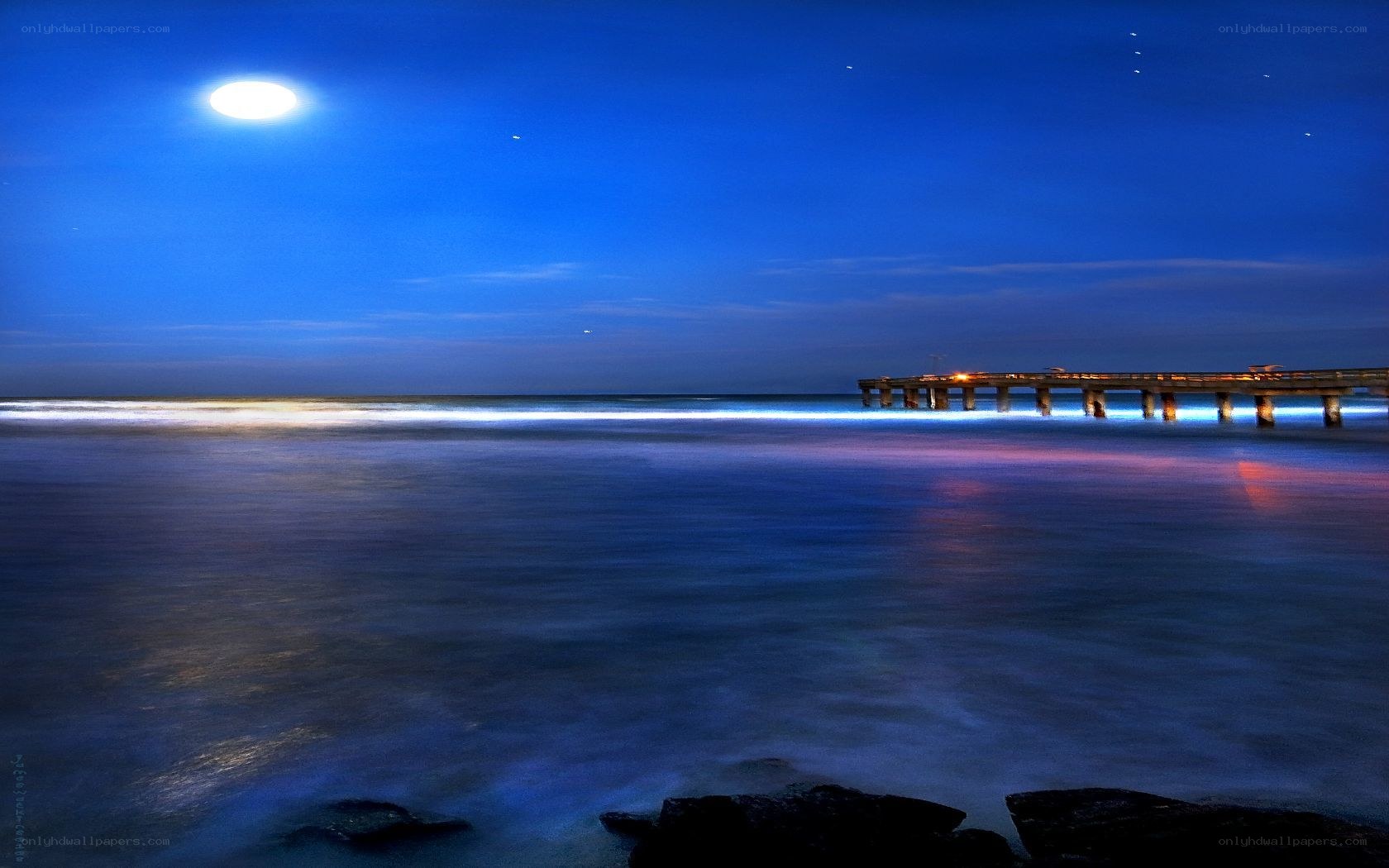 Moonlit pier at night