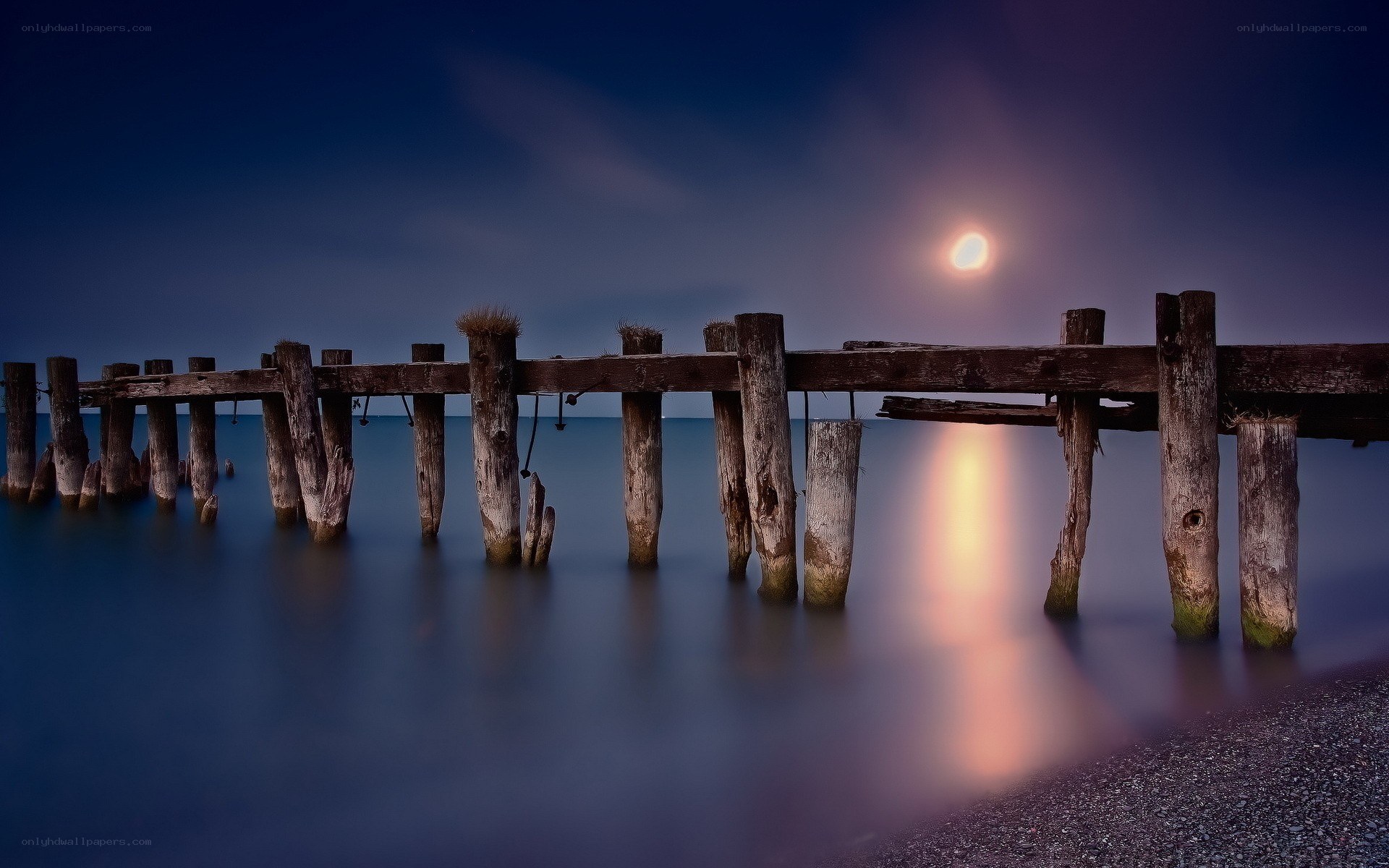 Moonlit pier at night