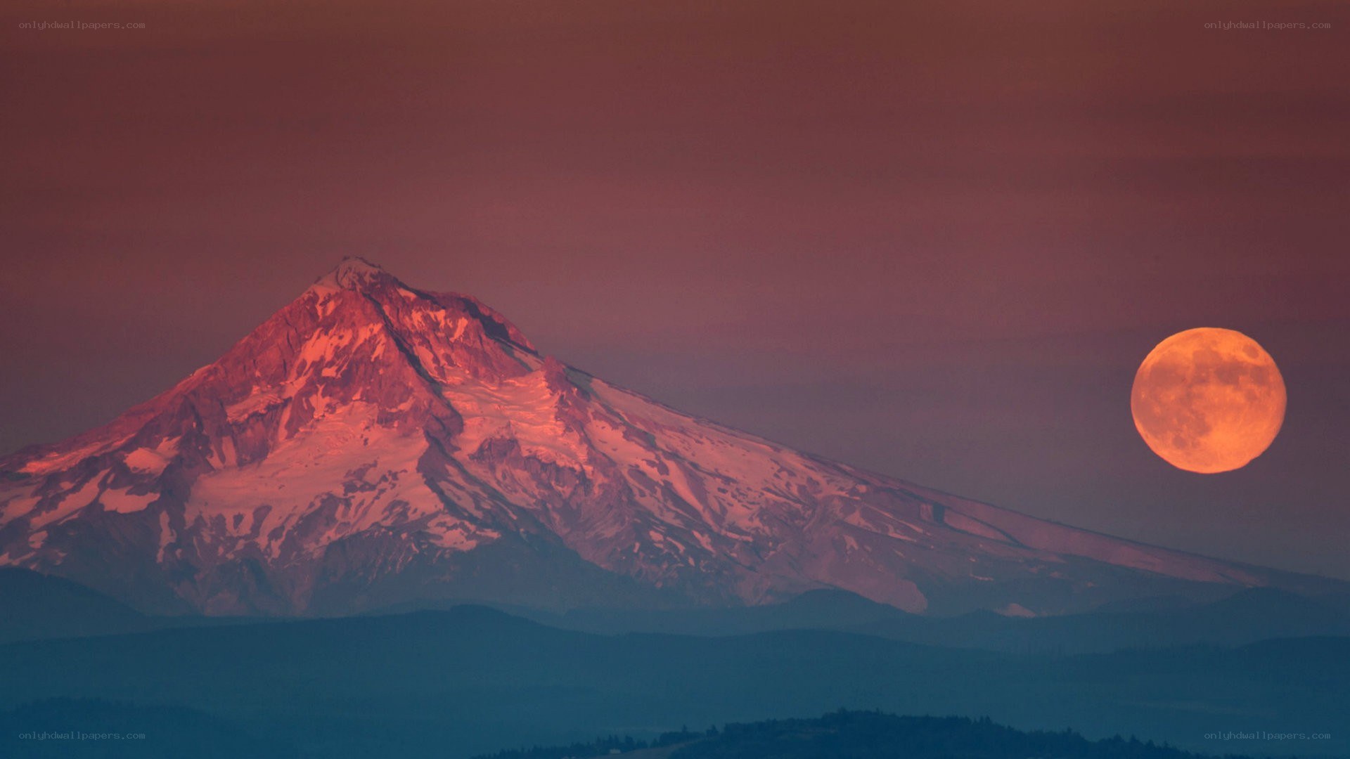 Moonrise over a snow-capped mountain