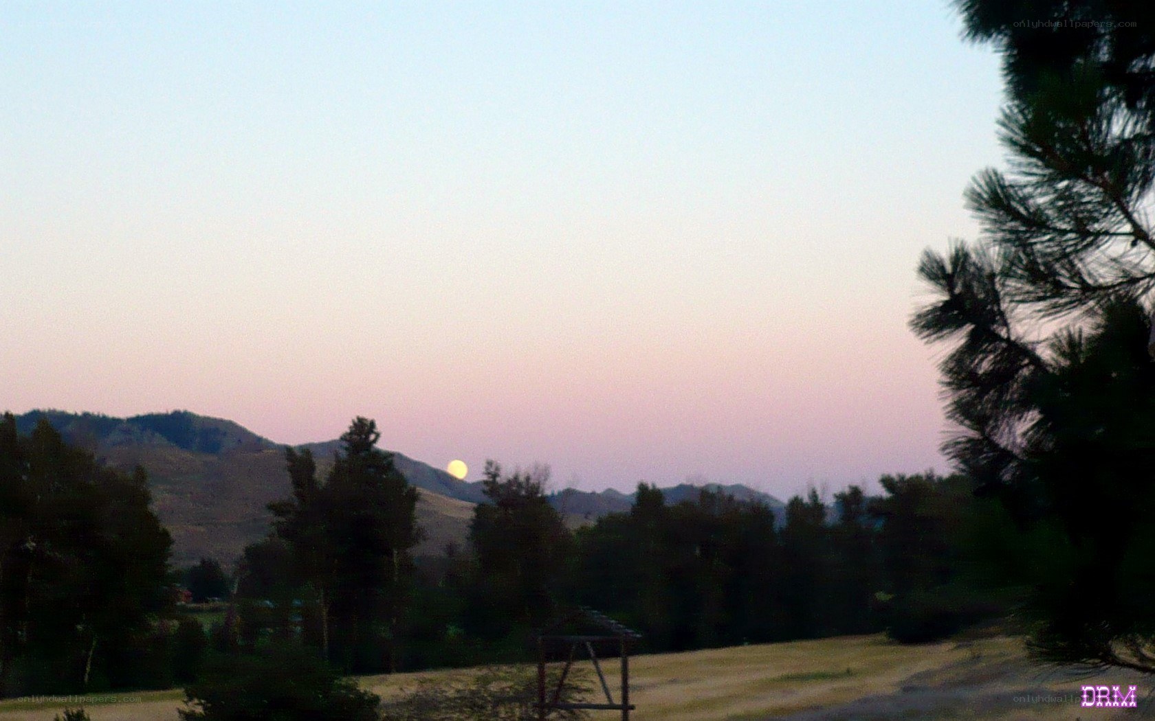 Moonrise over hills at dusk