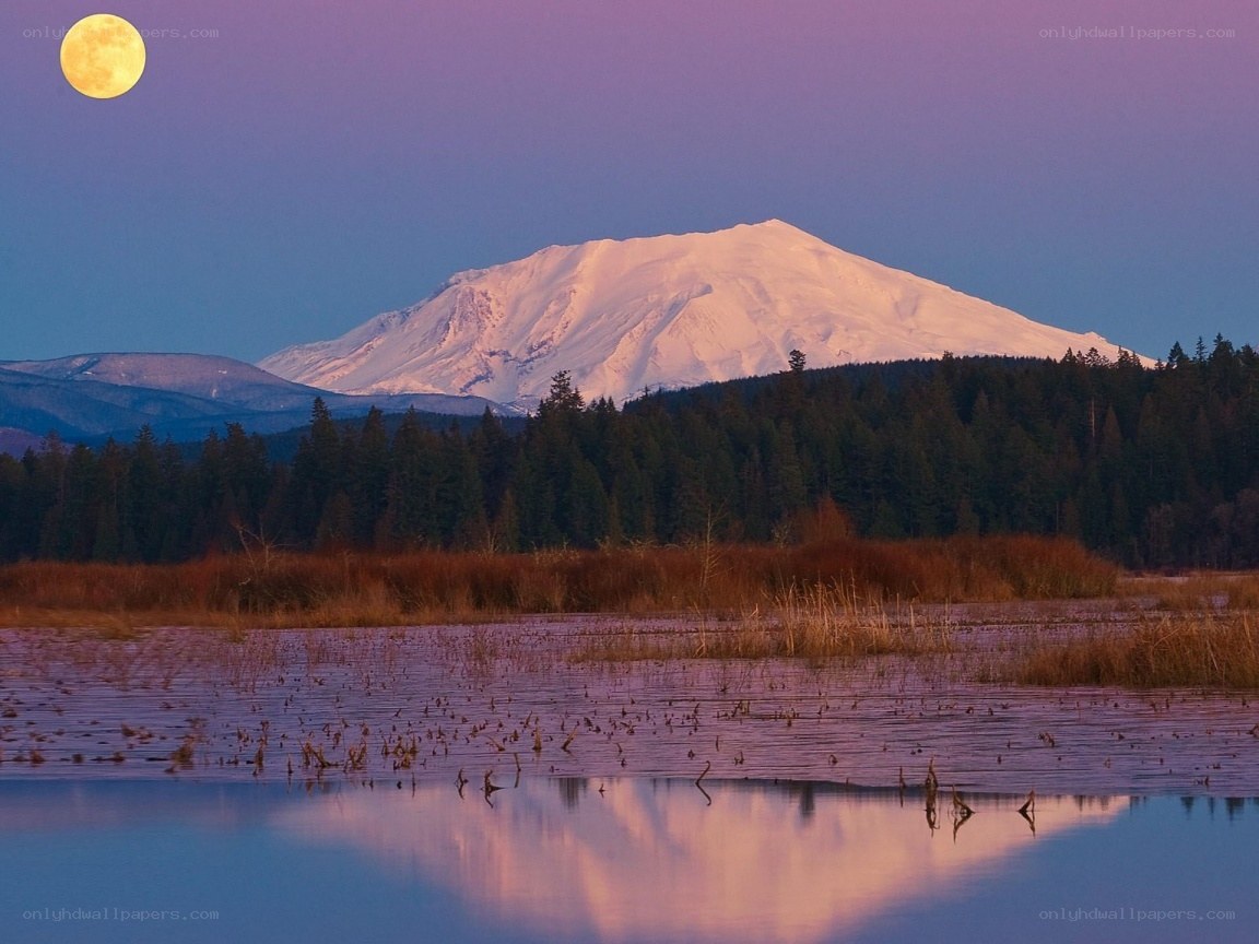 Moonrise over snow-capped mountain
