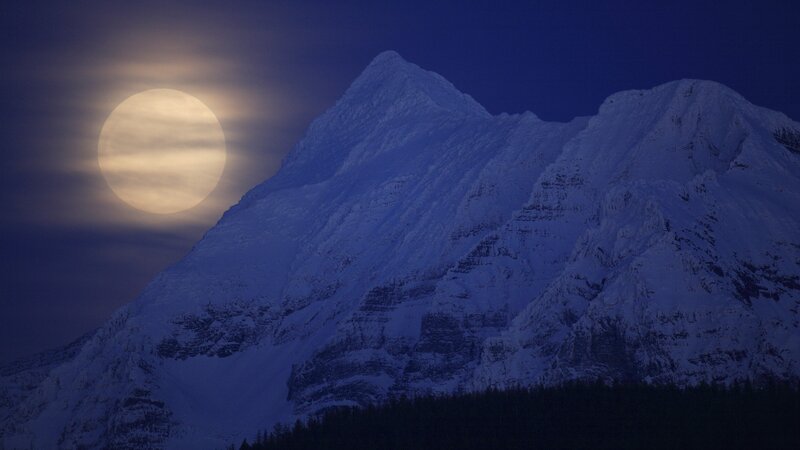 Moonrise over snow-capped mountains