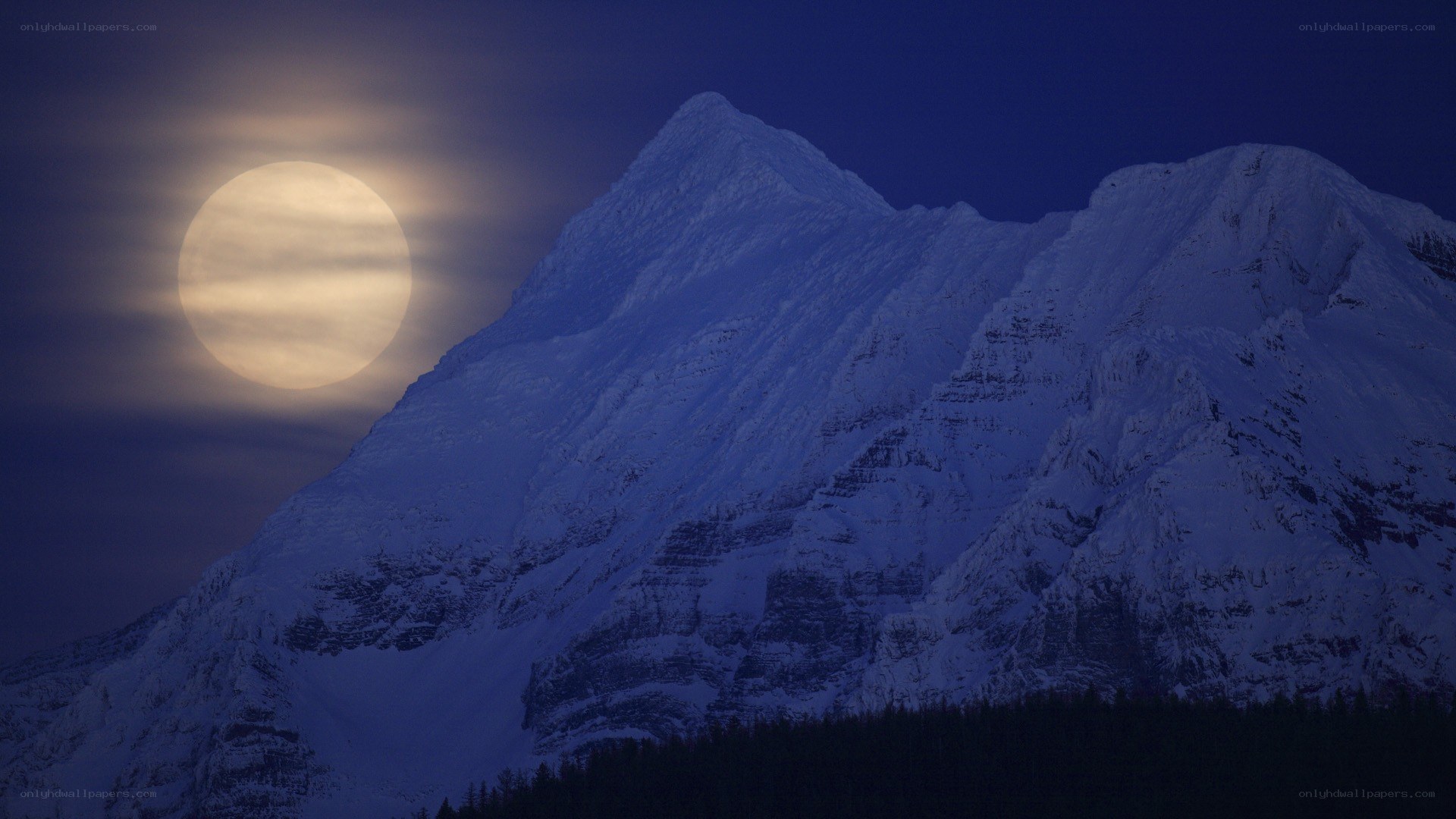 Moonrise over snow-capped mountains