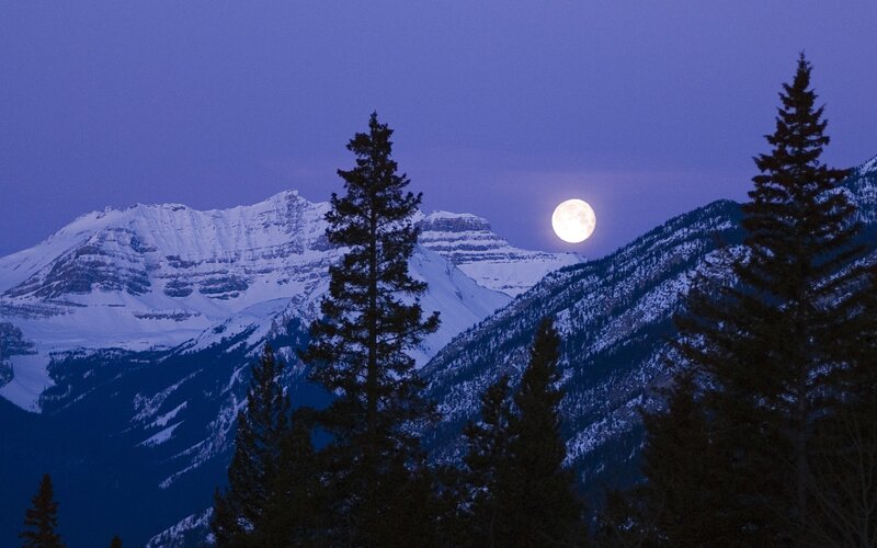 Moonrise over snow-capped mountains