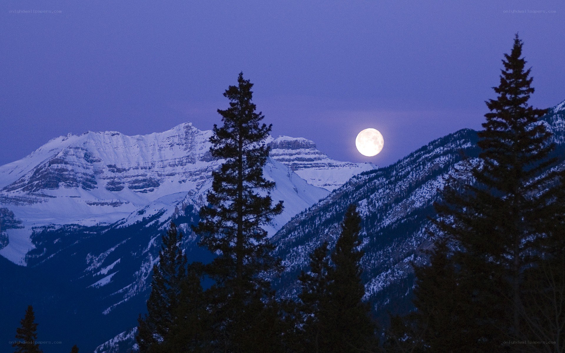 Moonrise over snow-capped mountains