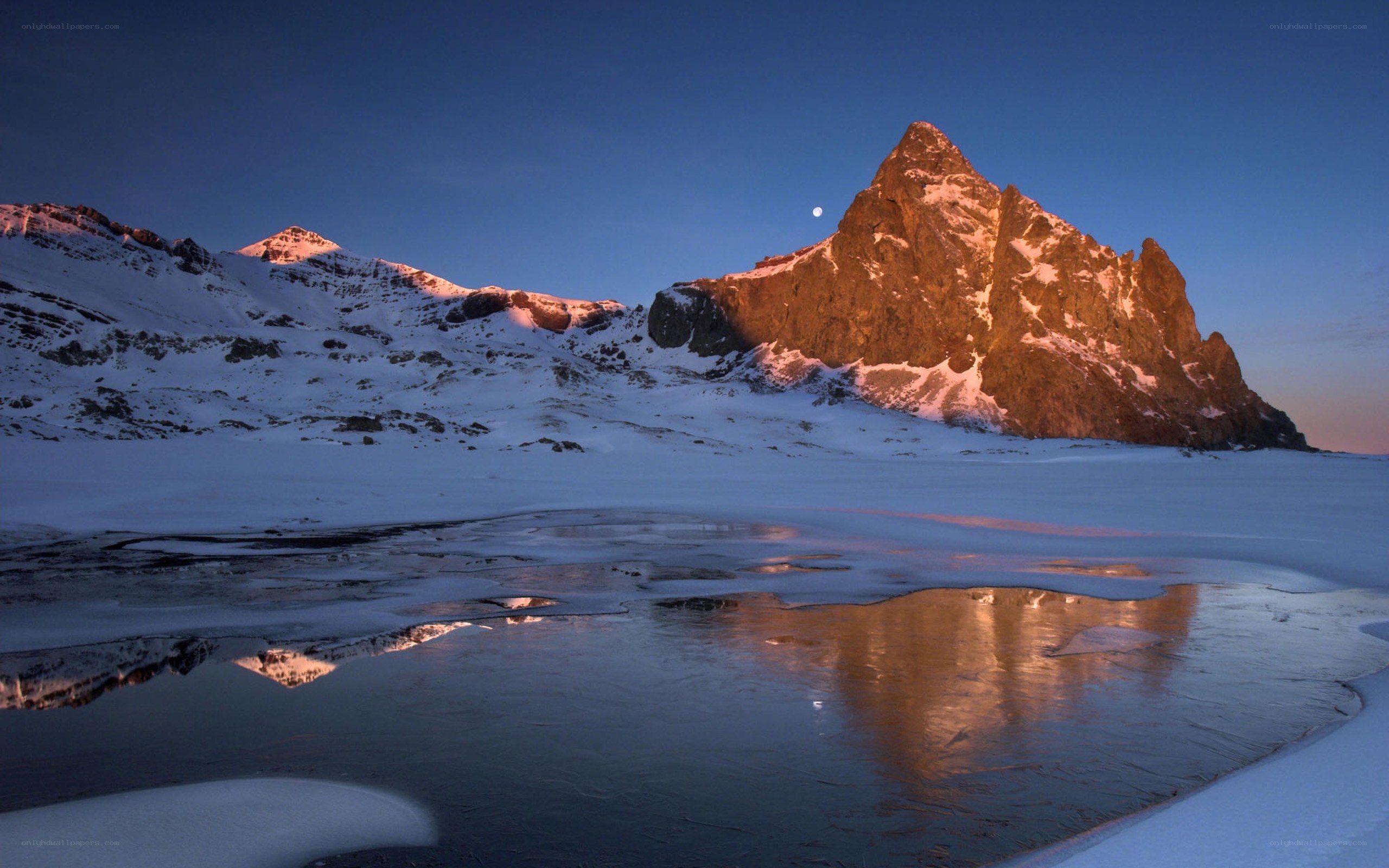 Moonrise over snow-capped mountains