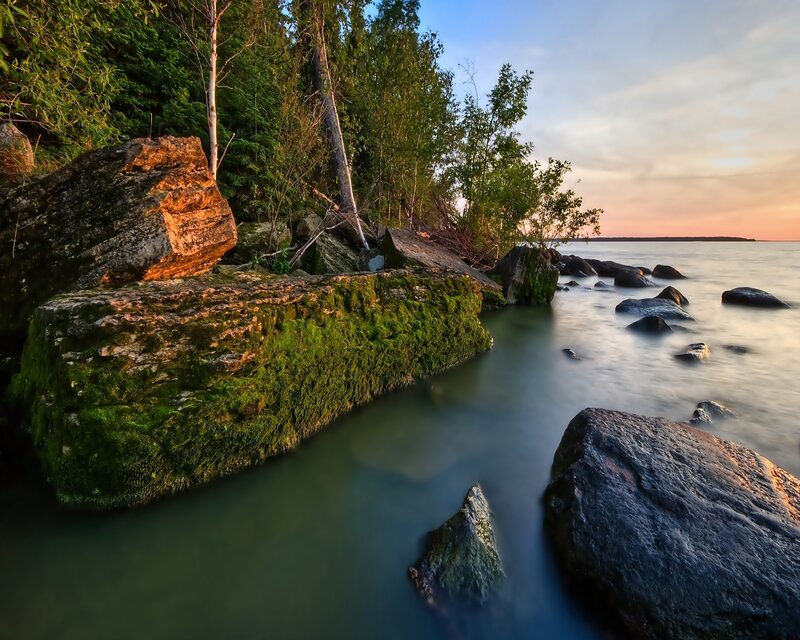 Moss-covered Rocks at Shoreline — Green, Serene, Sunset, Photograph, Trees, Water