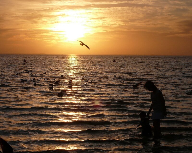 Mother and child at sunset by the sea