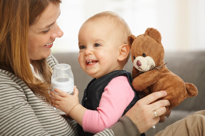 Mother feeding baby with teddy bear