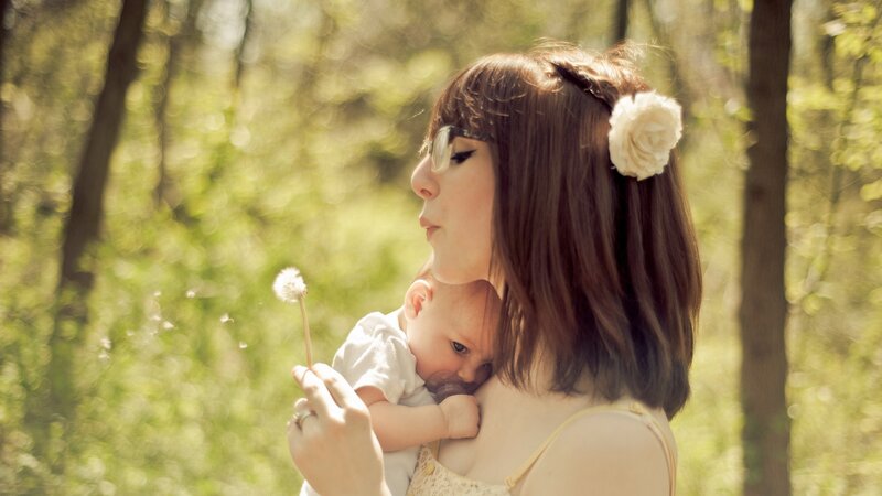 Mother holding baby with dandelion