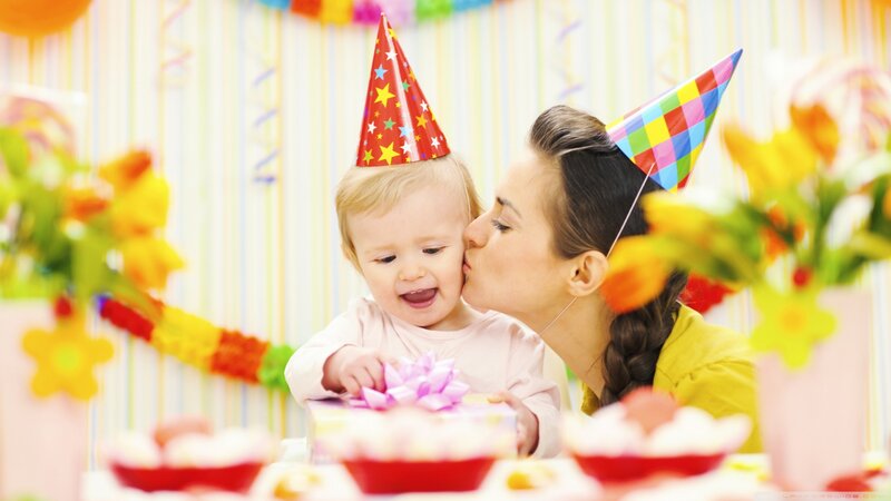 Mother kissing baby at birthday party