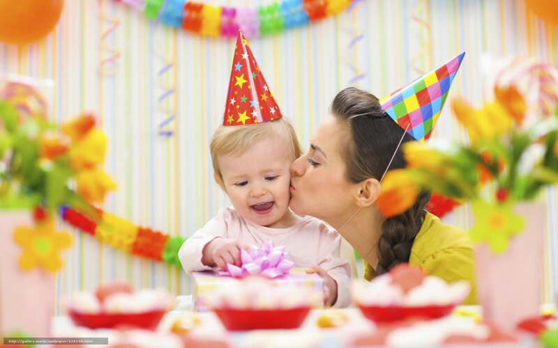Mother kissing baby at birthday party