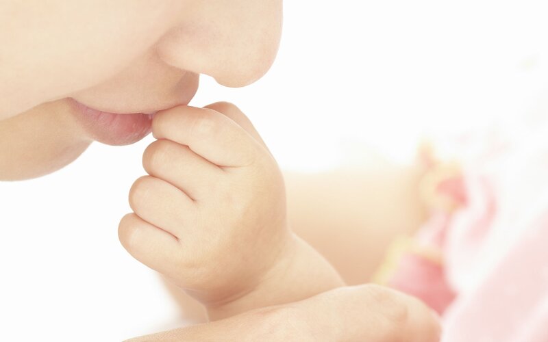 mother kissing baby's hand
