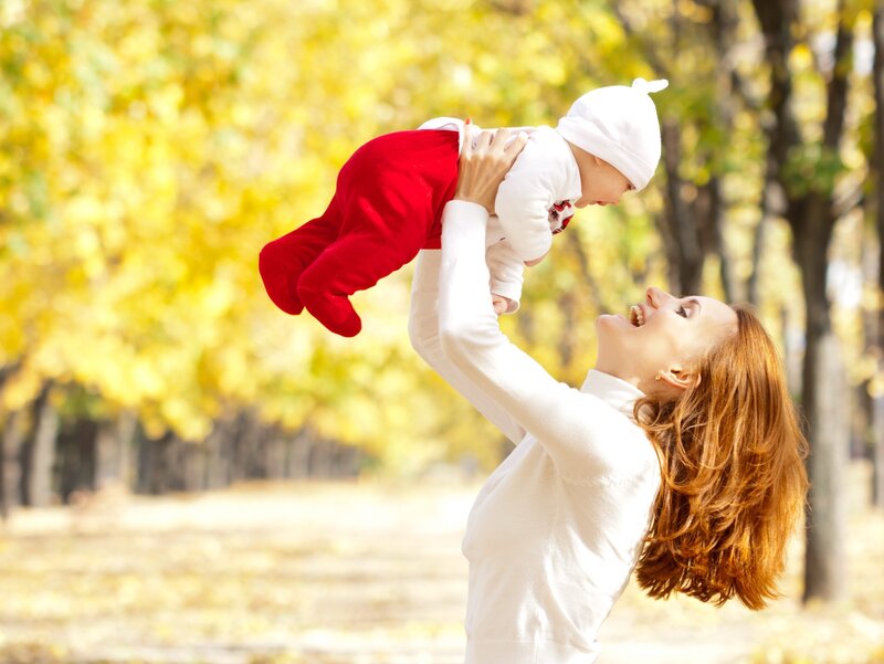 Mother playing with baby in autumn