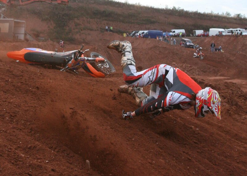 Motocross rider falls on dirt track