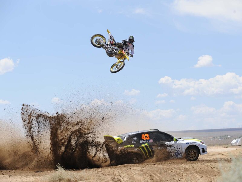 Motocross rider jumps over rally car