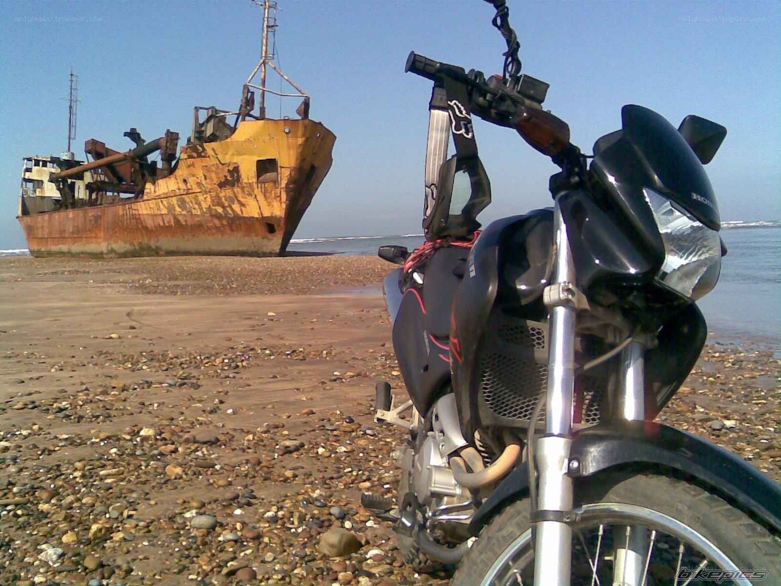Motorcycle on a beach with shipwreck