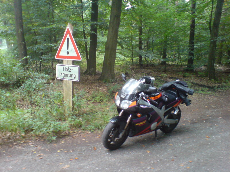 Motorcycle parked near forest sign
