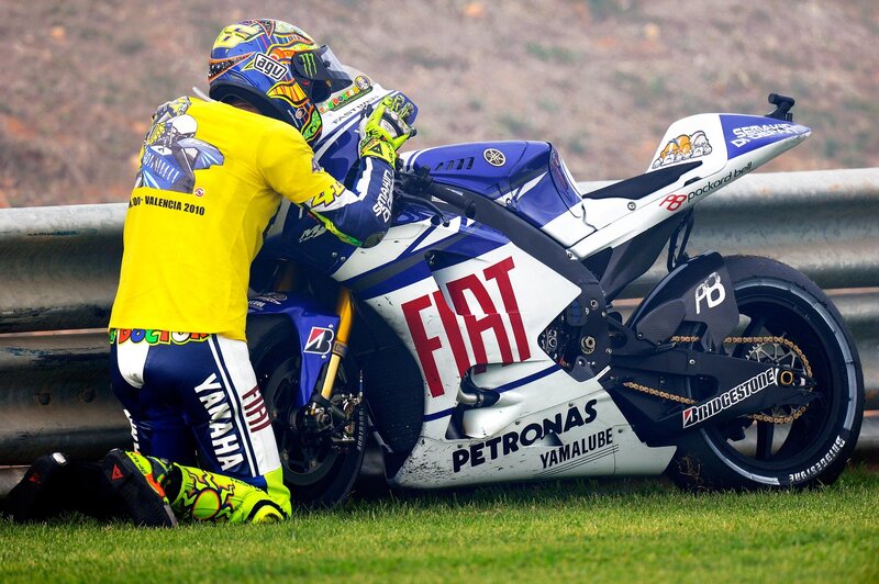 Motorcycle racer kneeling with bike
