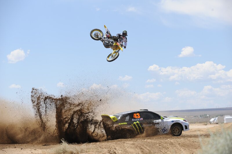 Motorcycle rider jumps over rally car