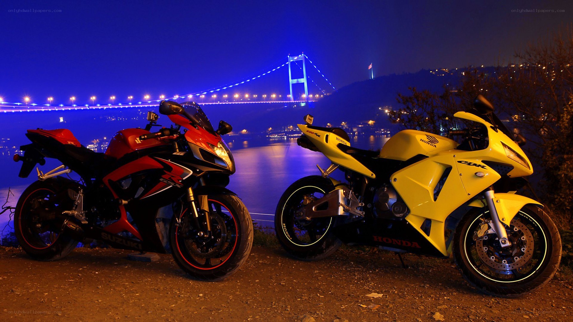 Motorcycles at night by a bridge