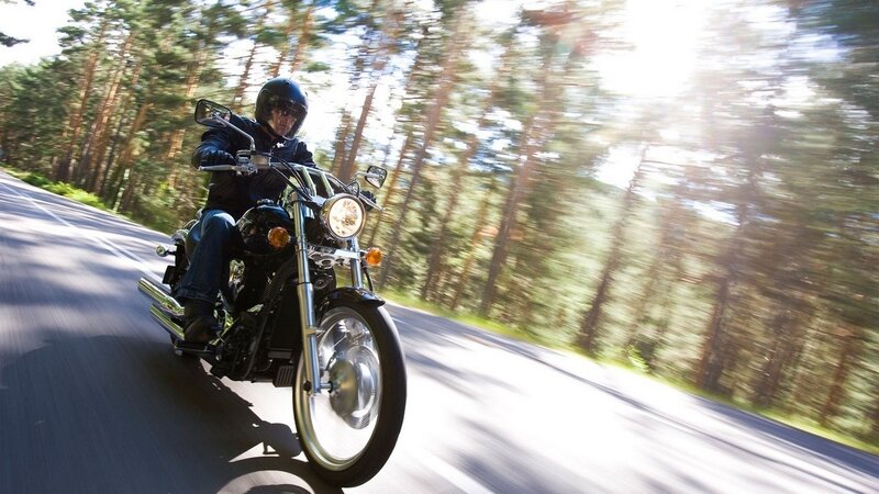 Motorcyclist riding on forest road