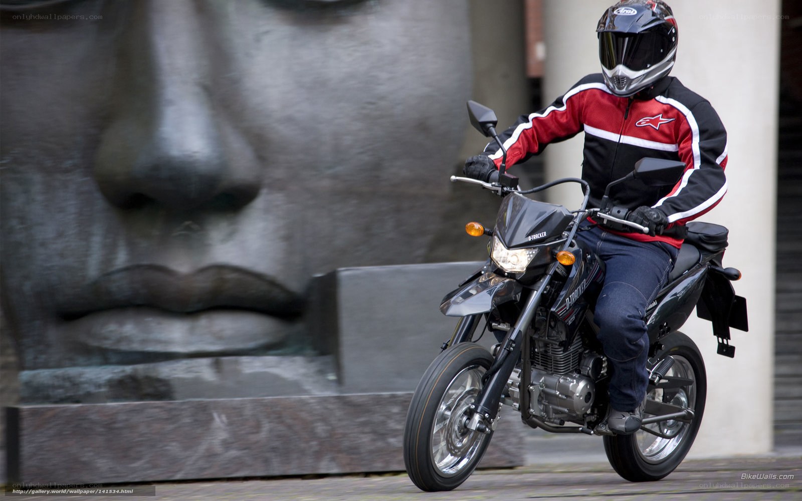 Motorcyclist riding past sculpture