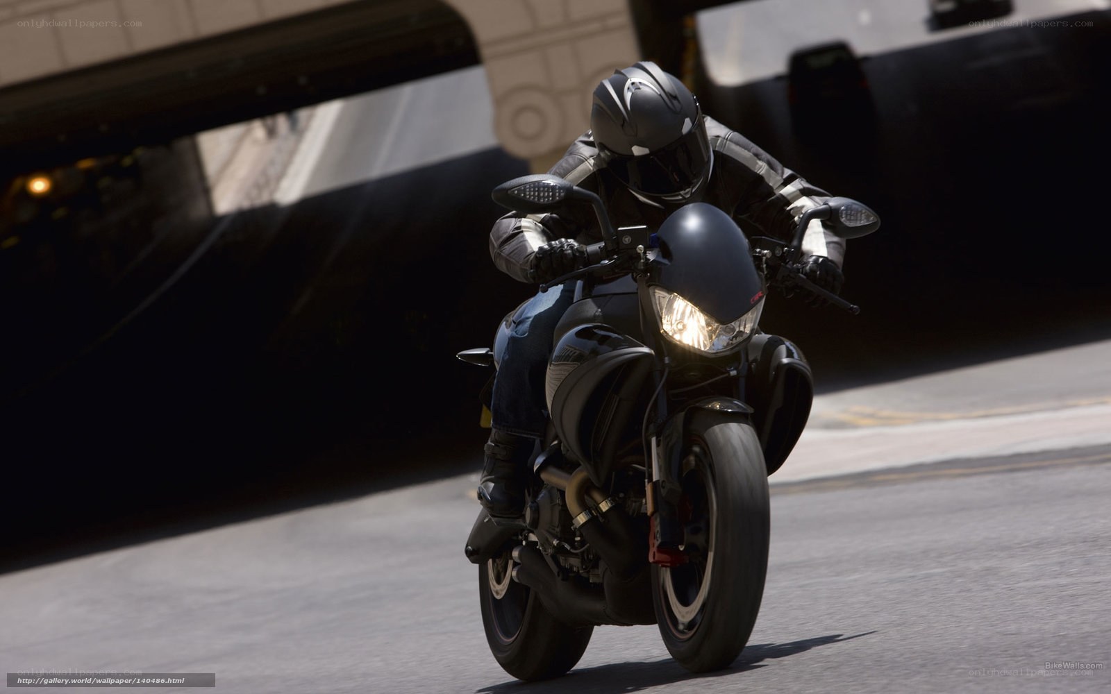 motorcyclist riding under bridge