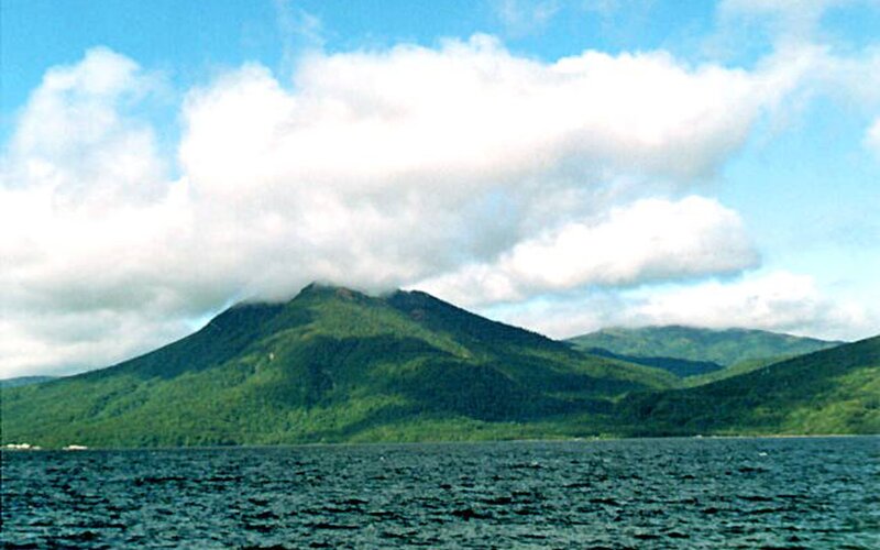 Mountain by a lake with clouds